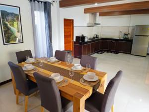 a dining room with a table and chairs and a kitchen at Baan Suan Sawan Villa in Krabi