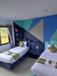 two beds in a room with a painting on the wall at Baan Suan Sawan Villa in Krabi +28 photos