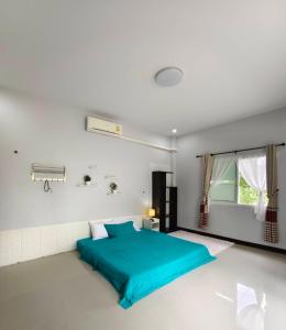 a bedroom with a blue bed in a white room at BaanRatsitornHomestay in Langu