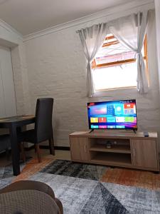 a living room with a tv and a table and a window at The Berna in Cape Town +6 photos