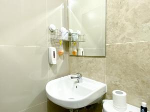 a bathroom with a sink and a mirror and a toilet at Best Deal and Cozy Studio Room Transpark Cibubur Apartment By Travelio in Depok