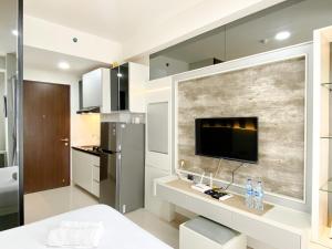 a kitchen with a flat screen tv on a wall at Best Deal and Cozy Studio Room Transpark Cibubur Apartment By Travelio in Depok