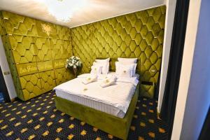 a hotel room with a bed with white sheets and pillows at Emir Palace in Popeşti-Leordeni