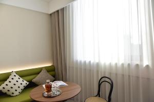 a room with a green couch with a table and a window at Beijing Tiananmen Wangfujing Ruibeting Apartment Hotel in Beijing