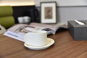 a white coffee cup sitting on a table with a book at Beijing Tiananmen Wangfujing Ruibeting Apartment Hotel in Beijing