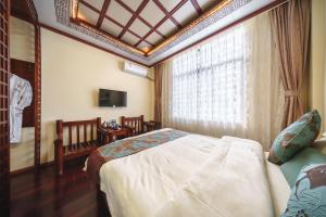 une chambre avec un lit, une fenêtre et une télévision dans l'établissement Dali Classical Rosewood Boutique Inn, à Dali 1 autre photo