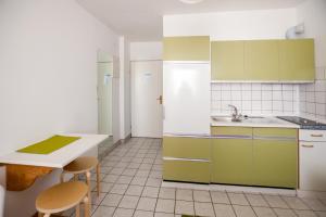 una cocina con armarios verdes y blancos y una mesa en Friendly People's Guest House, en Zadar