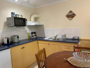 a kitchen with a table and a microwave at Banksia Cottage in Perth Hills in Perth