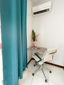 a desk and a chair in a room with a blue curtain at Appartement Papeete-Airport, Parking, wifi,AC,Pool in Papeete