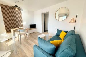 a living room with a blue couch and a mirror at Pieds Dans L'Eau T2 Archi Cosy - Vue mer 180 in Ploemeur