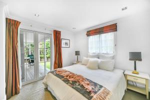 a white bedroom with a bed and a balcony at Cooks Cottage 2-4 Bedroom- Russell Cottages Collection in Russell