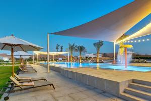 a swimming pool with lounge chairs and an umbrella at Liwa Guest House in Z̧afīr