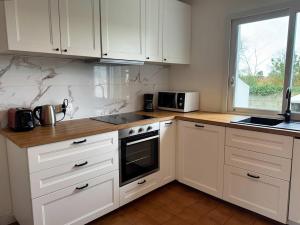 Una cocina con gabinetes blancos, un fregadero y un microondas. en l'Echappee belle Seaside break for 8 people, en Plougasnou