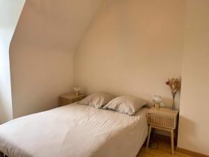 Un dormitorio con una cama blanca con dos mesitas de noche. en l'Echappee belle Seaside break for 8 people, en Plougasnou