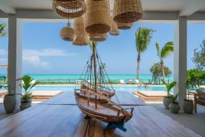 a wooden boat on a table in a room with a pool at Kaskazi Hotel Zanzibar in Jambiani