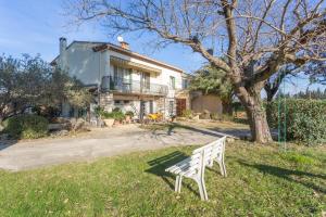 Le Mélomane - Maison climatisée avec jardin clos في Montfrin: مقعد أبيض يجلس على العشب أمام المنزل