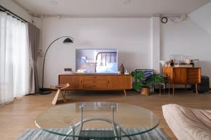 sala de estar con TV y mesa de cristal en Wit Haus Nimman, en Chiang Mai