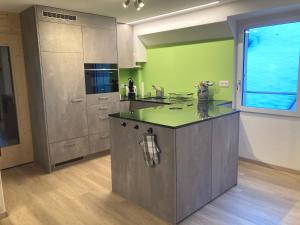 a large kitchen with green walls and a large island at Appartamento Evelina in Airolo
