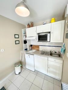 a kitchen with white cabinets and a microwave at T2 Top Cosy Balcon 150m des plages in Carnac