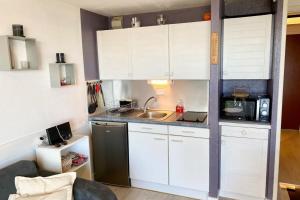 Una pequeña cocina con gabinetes blancos y un fregadero. en Joli appartement Cocooning Vue mer 180, en Ploemeur 19 fotos más