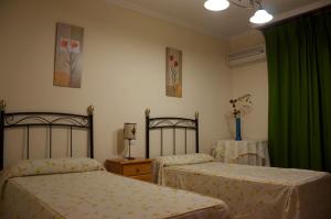 a bedroom with two beds and a green curtain at Pensión Matilde in Granada