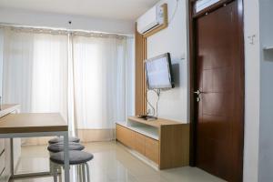 バンドンにあるSpacious and Tranquil 2BR Apartment Gateway Pasteur By Travelioのテレビとテーブルとスツールが備わったホテルの部屋