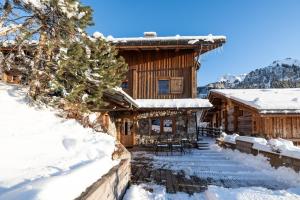 una cabaña de madera en la nieve con mesas y sillas en Coeur de neige 1724, en Le Grand-Bornand