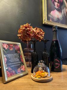 a table with vases and a bottle of wine and flowers at Suite Josefina - SPA&SAUNA - au cœur de la route des vins in Rorschwihr