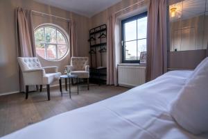 a bedroom with a bed and two chairs and a window at LouLou in Berg en Terblijt