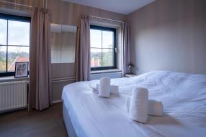 a bedroom with a large white bed with two chairs at LouLou in Berg en Terblijt +54 photos