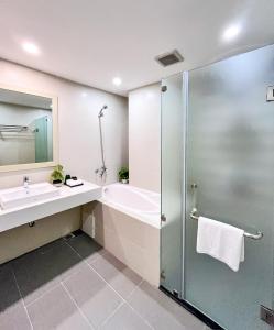 a bathroom with a tub and a sink and a shower at XÔI Setai Suites Linh Lang in Hanoi