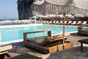 a swimming pool with chairs and umbrellas at Maya Beach Resort in Massa Lubrense