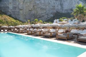 a pool with chairs and umbrellas next to a mountain at Maya Beach Resort in Massa Lubrense