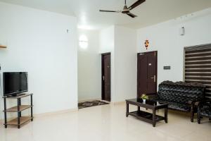 a living room with a couch and a tv at Athirappilly Ambady Resort in Athirappilly