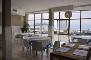 a restaurant with tables and chairs and a view of the ocean at Hostal del Rey in Puerto Madryn