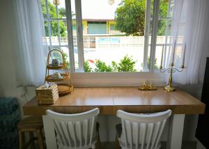 a table with two white chairs and a large window at Ban Ye in Phayao
