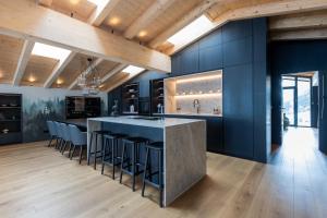a kitchen with blue walls and a large island with bar stools at Hotel Madlein in Ischgl +158 photos