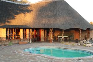 eine strohgedeckte Hütte mit einem Pool davor in der Unterkunft Torgos Lodge in Koës