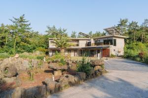 a house with a stone wall in front of it at By Hanlim in Jeju