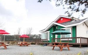a green and red building with picnic tables and umbrellas at Taean Mongsanpo Pine and Apple Pension in Taean