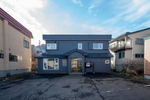 a blue house in a parking lot next to some buildings at THE Crocus Otaru in Otaru