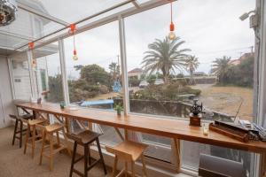 a large window in a house with a table and chairs at Jeju Ddoolle Pension in Jeju