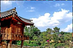 a small wooden building with a roof in front of trees at Manhoe Gotaek in Bonghwa