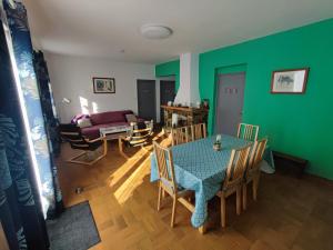 ein Wohnzimmer mit einem Tisch, Stühlen und einer grünen Wand in der Unterkunft Au pont de Tuarelli, Ludique, Galeria, Corse in Manso