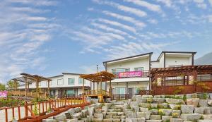 a white building with a fence and some rocks at Namhae Uyeongwa Inyeon Pension Uyeon in Namhae