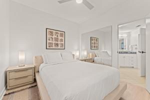 a white bedroom with a large bed and a living room at Tides 611 in Destin