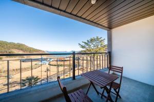 a balcony with a table and chairs and a view of the beach at Yeosu Secretgarden Pension in Yeosu