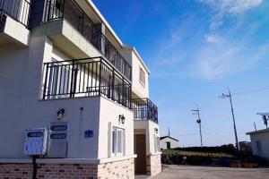 a white building with a balcony on top of it at Udo Sarangchae Pension in Jeju