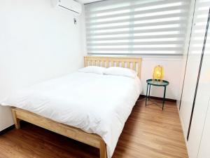 a bedroom with a white bed and a small table at Jeju Hyeopjae Life in Jeju