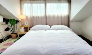 a large white bed in a room with a window at Jeju Hyeopjae Life in Jeju